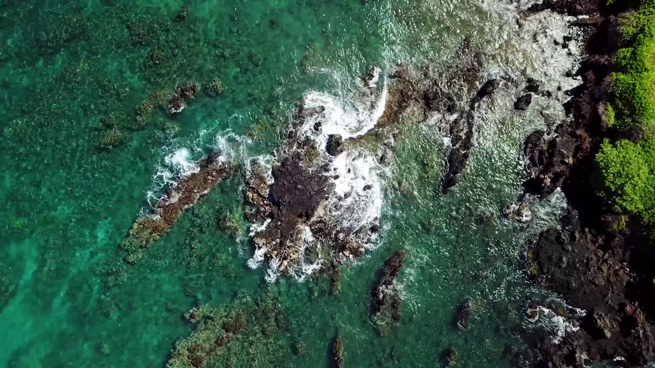 un dron, ojo de pájaro, vista aérea, de arriba hacia abajo de las olas rompiendo contra las rocas y la costa en wailea, una hermosa zona con playas de arena blanca y agua verde azulado en la isla de maui, hawaii