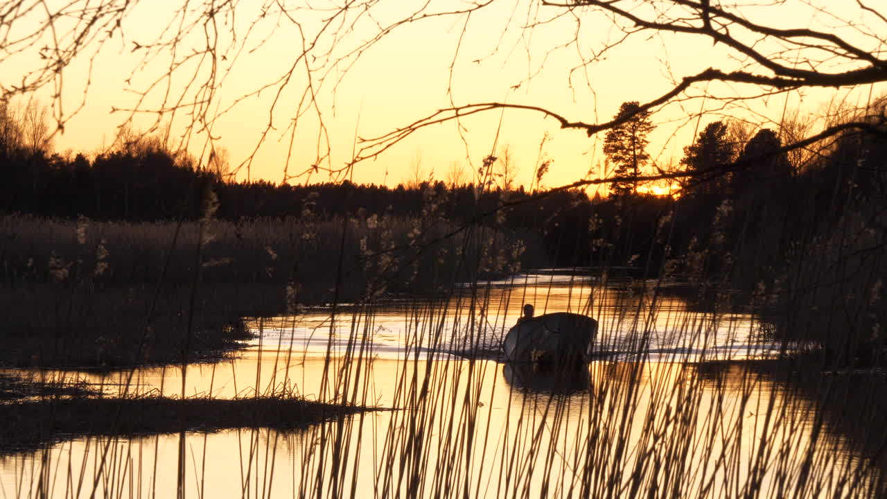 bote pequeño conduciendo sobre el agua del río marsh a la luz del atardecer, verano en finlandia