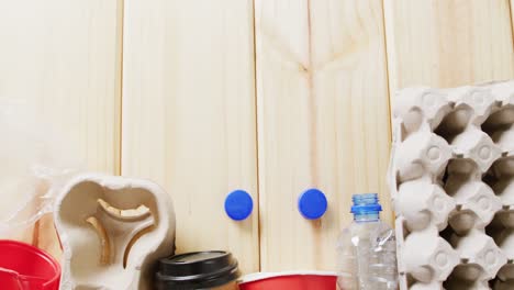 close up of paper, plastic and glass trash on wooden background, with copy space