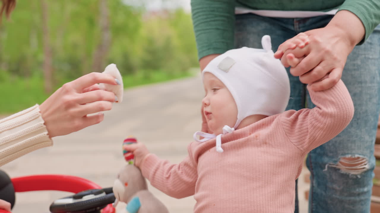 Little One Begins To Explore Outdoors Step By Step, Small Kid Takes Tentative Strides In Park Area, Youngster Embarks On Outdoor Walking Adventures With Careful Movements And Support
