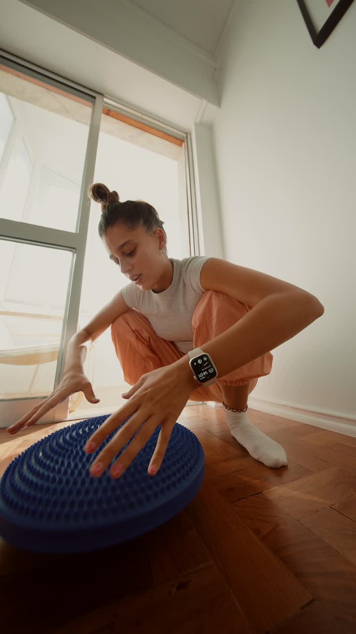 Woman exercising with a balance cushion indoors
