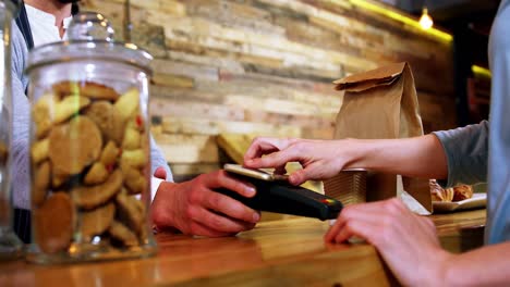 mujer pagando facturas a través de un teléfono inteligente utilizando tecnología nfc