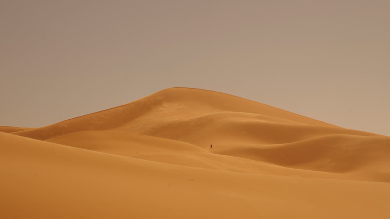Towering Sahara dunes in Morocco glow with golden tones beneath the sunset light