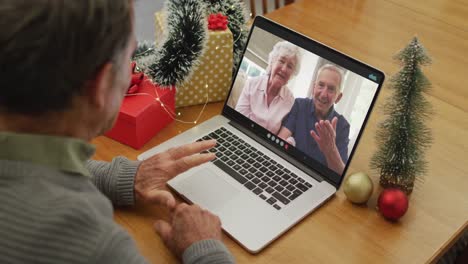 Happy-caucasian-senior-man-on-video-call-with-senior-friends-at-christmas-time