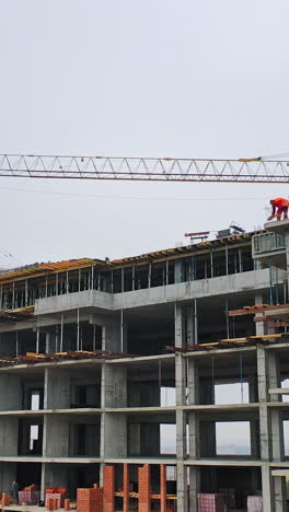 drone view on a new construction site. working process of construction the modern building on the background of two big cranes in the city. vertical video
