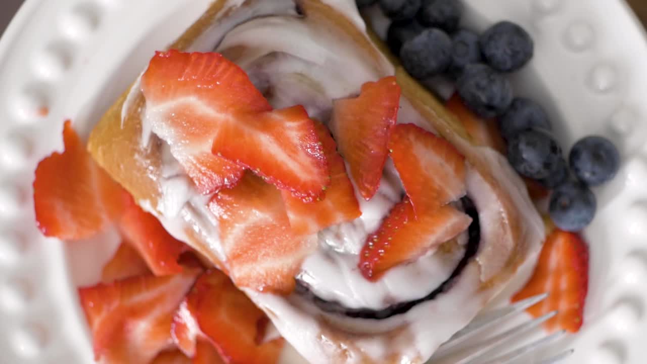 Homemade Frosted Cinnamon Bun with Blueberries and Strawberries on Plate