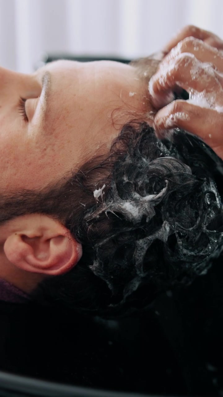 Barbiere professionista che lava i capelli a un cliente in salone