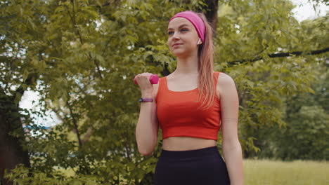 Chica-Atlética-Joven-En-Forma-Deportiva-Haciendo-Ejercicios-Con-Pesas-En-El-Parque-Soleado-Realizando-Ejercicio-De-Bíceps