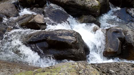 Rocky-waterfall-river-creek-flowing-over-boulders-in-seasonal-Autumn-woodland-looking-down-dolly-right