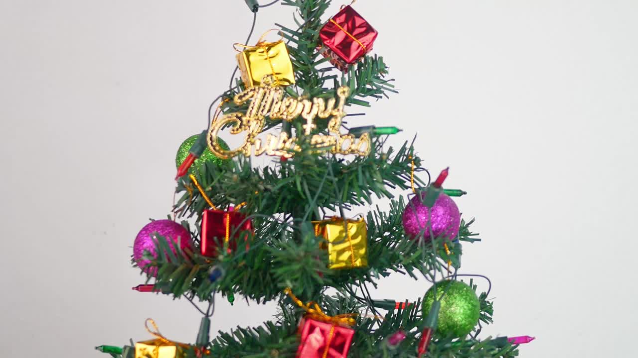 색 배경에 고립 된 새해 2020 년을 위해 baubles, 조명 및 작은 선물 선물로 장식 된 크리스마스 트리.