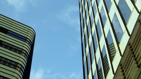 looking up at a juxtaposition of curved and angular modern skyscrapers against a blue sky