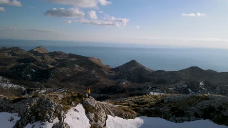 Man-hiking-peak-of-snowy-white-mountains-against-blue-Adriatic-Sea,-Sveti-Jure,-Biokovo,-Croatia