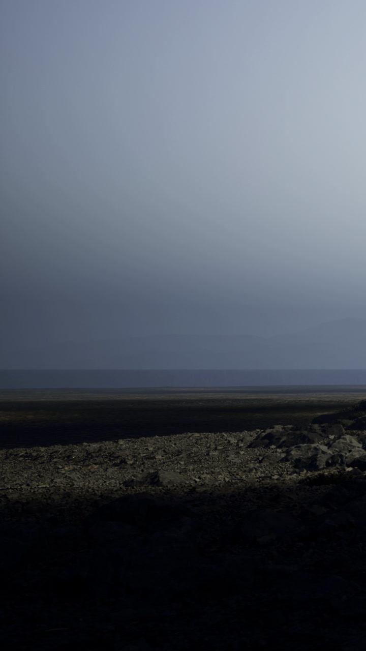 Dark landscape with a distant horizon at twilight near a calm shoreline