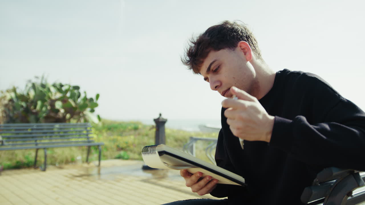 Man Searching For Inspiration And Ideas To Write On The Bench Near The Sea