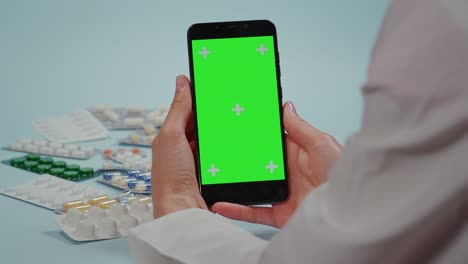 de cerca, la mano del médico usando el teléfono inteligente, pantalla verde