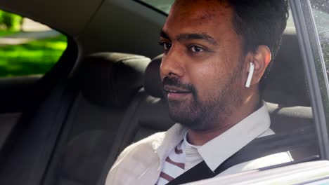 indian male passenger with earphones in taxi car.transport, business and technology concept happy smiling indian male passenger with wireless earphones on back seat of taxi car