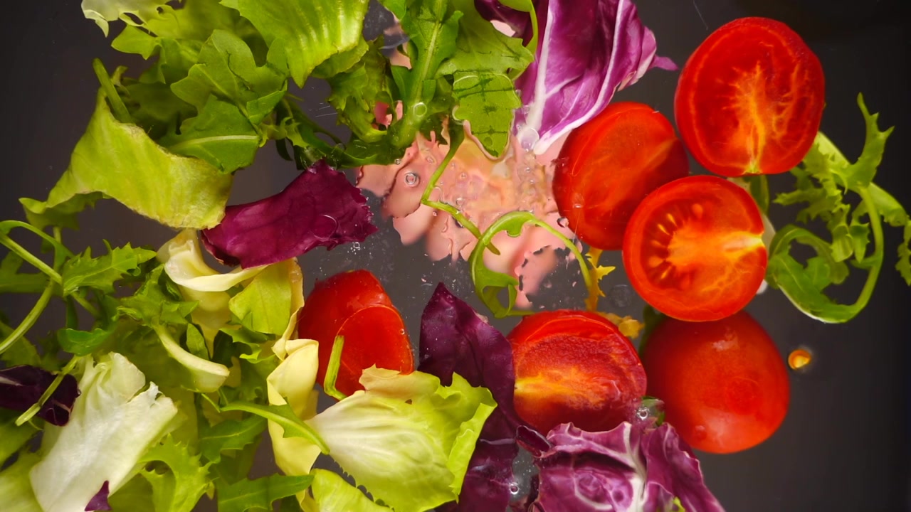 Aggiungere succo di limone a un'insalata fresca di pomodori ed erbe aromatiche in una ciotola di vetro. Vista dal basso