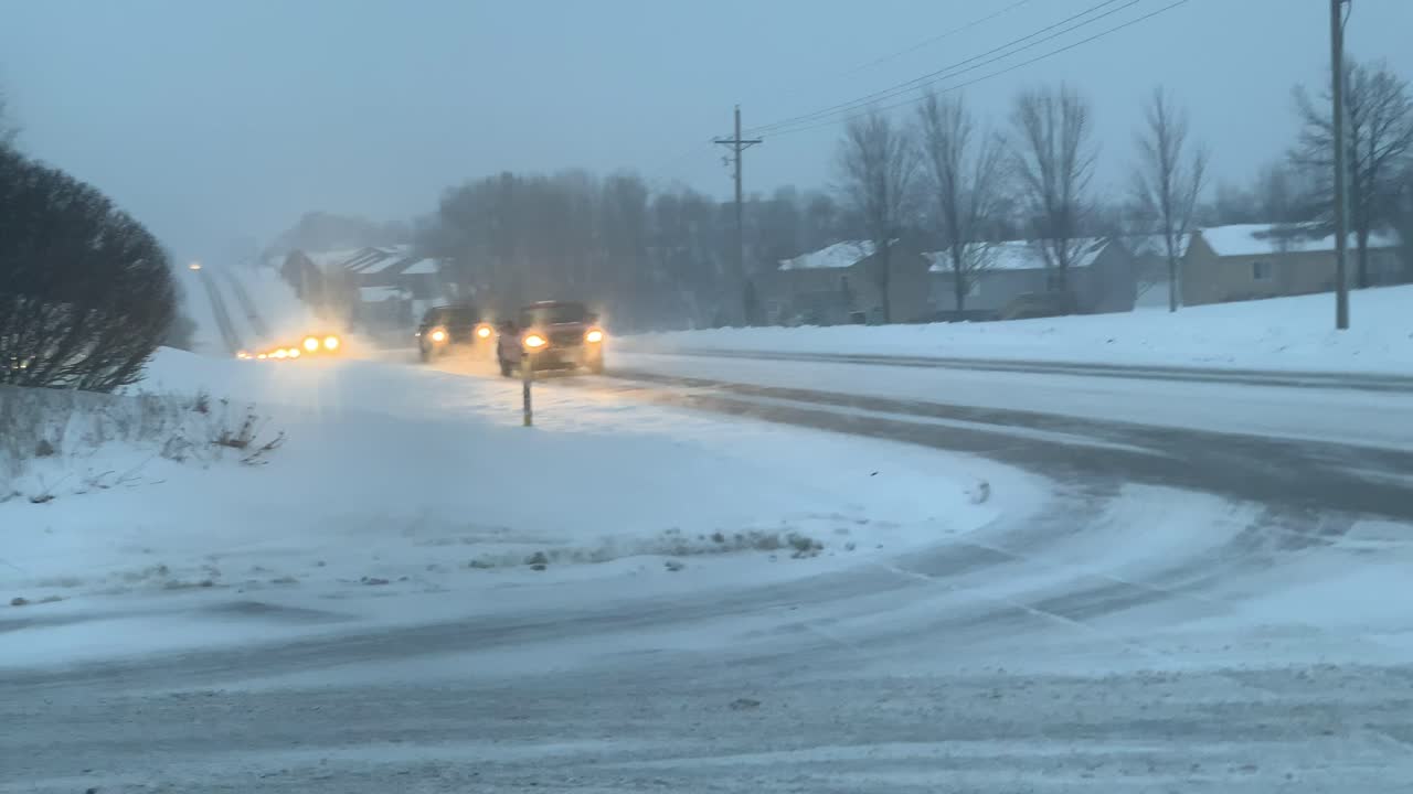 A series of cars driving by in the new wet snowy streets.