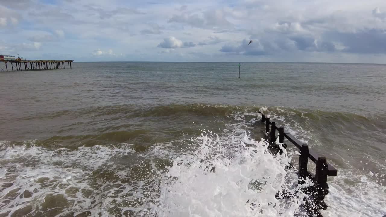 деревянный волнорез на пляже тигнмут с плещущимися большими волнами