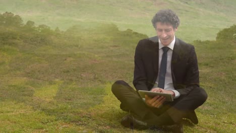 Businessman-typing-on-his-tablet-while-sitting-on-grass