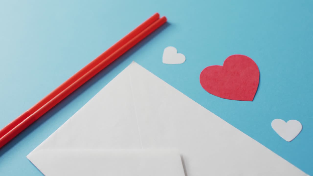 Straws with paper hearts and envelope on blue background at valentine's day