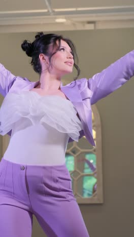 A Woman in a Purple Suit Dances Confidently in front of a Mirror a Woman in a Vibrant Purple Suit Dances Confidently in front of a Mirror Showcasing her Skill and Joy in a Stylish Room Embodying Creativity