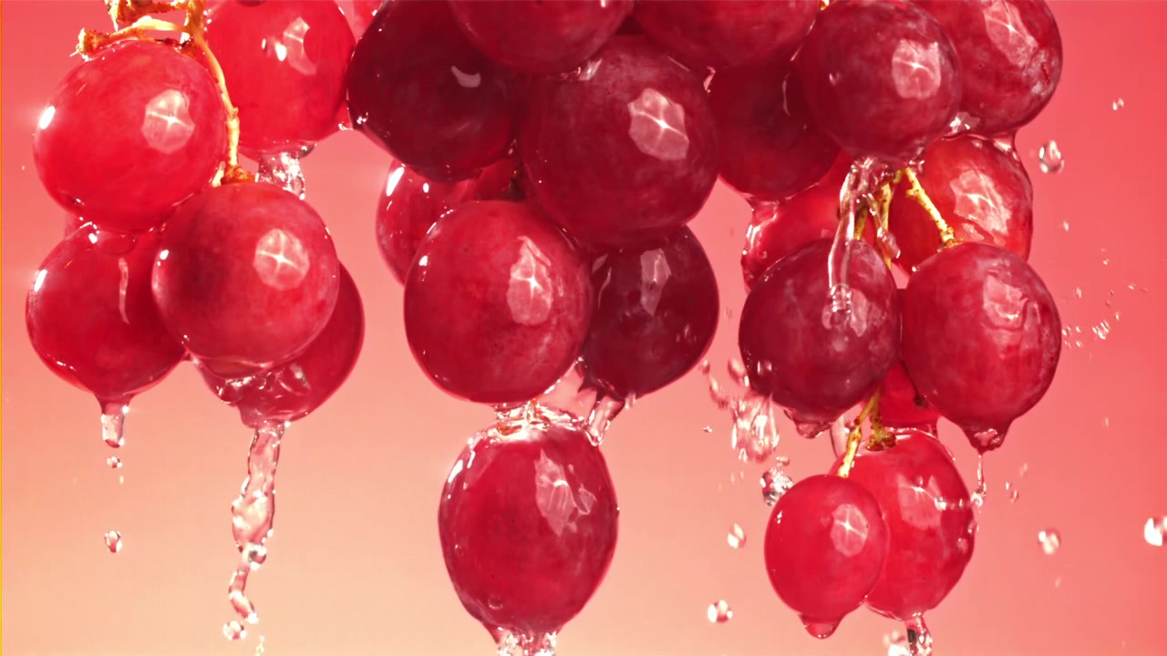 Uva rossa fresca con acqua che schizza e gocciola.