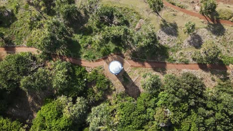 High-view-of-a-historic-lighthouse-and-pathways-surrounded-by-green-coastal-trees