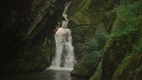 cascada espumosa salpica sobre el lago por la zanja de roca en el bosque de verano en cámara lenta. cascada de agua entre los acantilados de la montaña en la reserva nacional. belleza del desierto