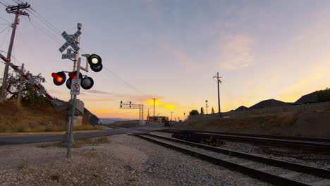 Cars-and-trucks-driving-over-a-railway-or-railroad-crossing-as-the-gate-begins-to-light-up-and-the-gates-begin-to-close