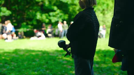 7-year-old caucasian boy with long blonde hair wearing a cap waiting in line with his carton-built rocket in a sunlit forest