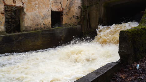 old hydro electro station sluice with strong water stream crashing in river