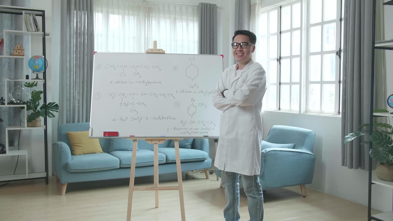 Asian Male Teacher With Glasses Crossing Arms And Smiling To Camera While Teaching Chemist At Home