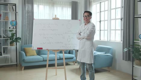 asian male teacher with glasses crossing arms and smiling to camera while teaching chemist at home