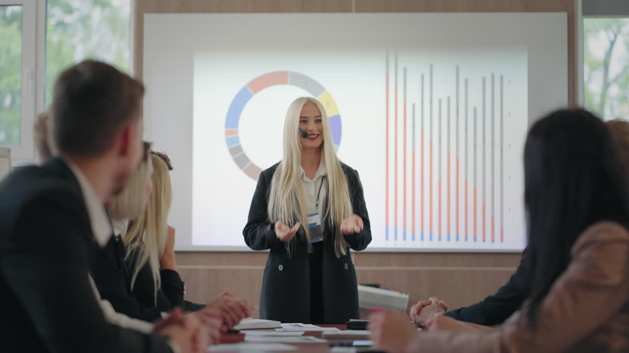 즐거운 금발 여성은 비즈니스 회의에서 이야기하고 차트에 대항하는 여성 전문가입니다.