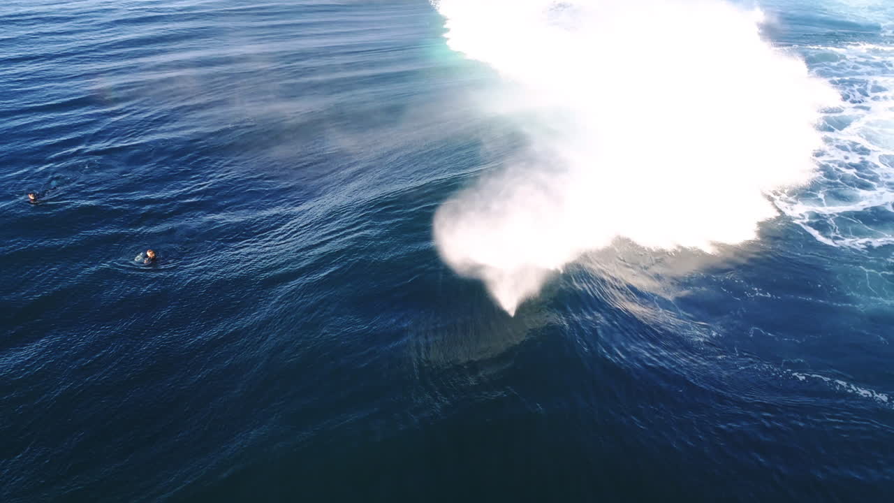 Aerial view of rolling wave with blue glistening texture and soft cresting curl