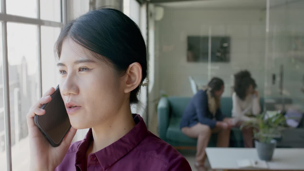 바쁜 아시아의 캐주얼 사업가 여성이 크리에이티브 사무실에서 스마트폰으로 이야기하고, 느린 동작