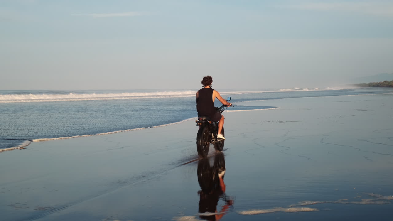 Uomo in moto su una spiaggia al tramonto
