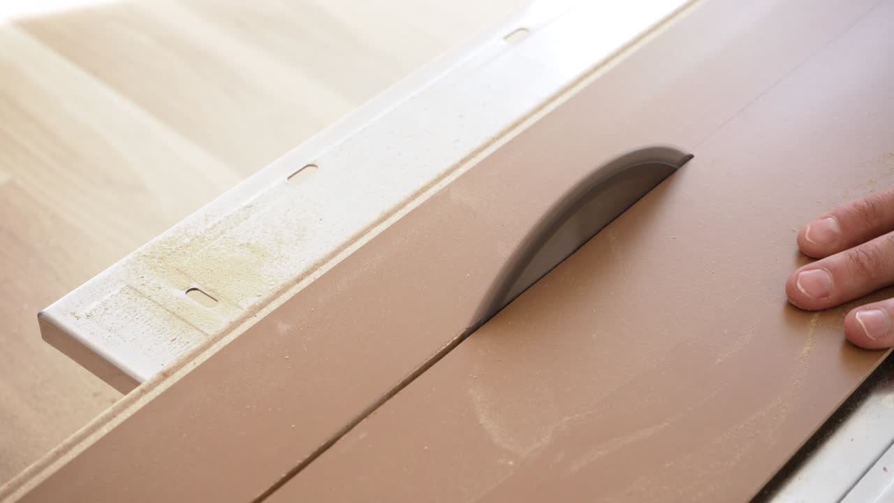 원형 도자기로 라미네이트 바닥 보드를 잘라내는 것, 회전하는 이빨에 대항하여 타일을 움직이는 사람의 손에 대한 세부 사항