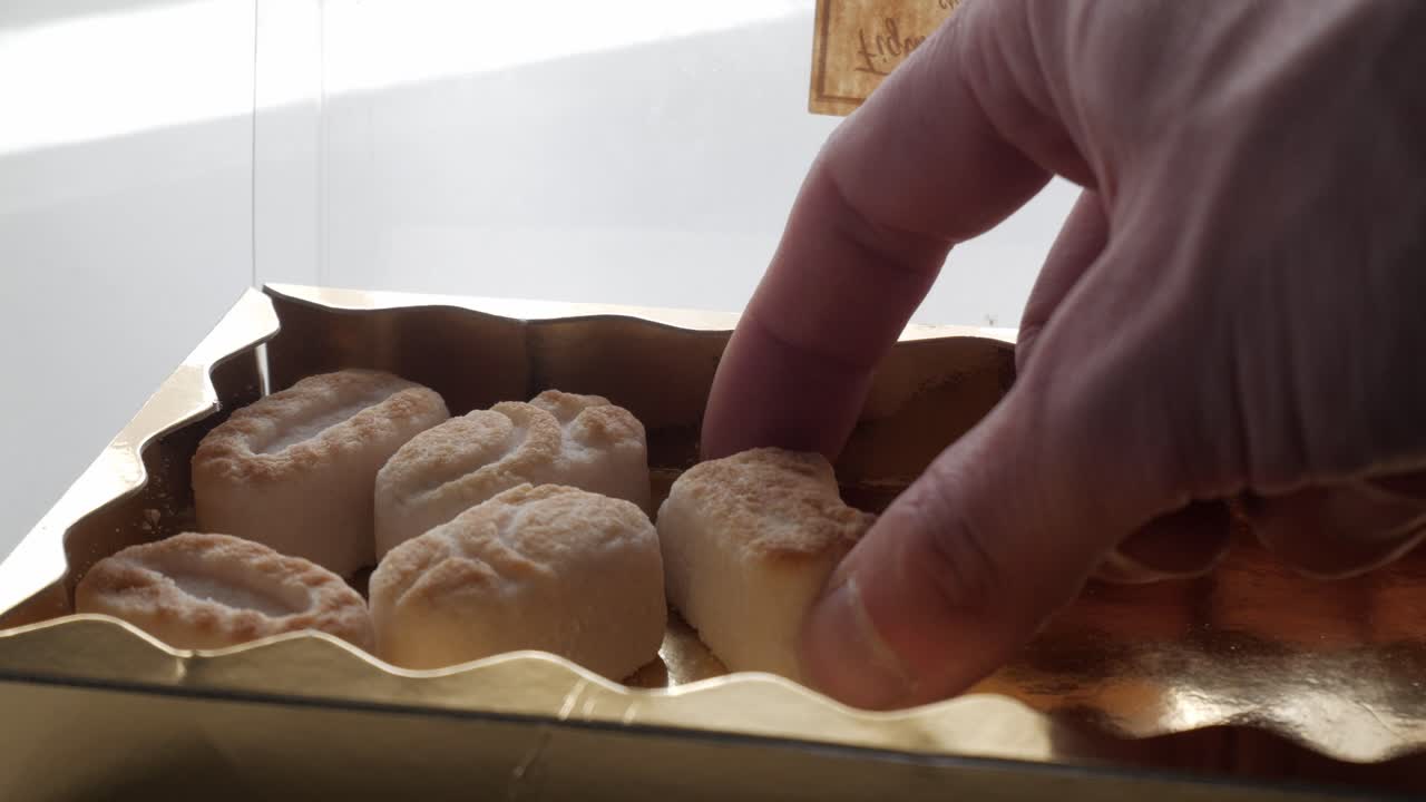 Hand selecting marzipan figures from a golden box for tasting