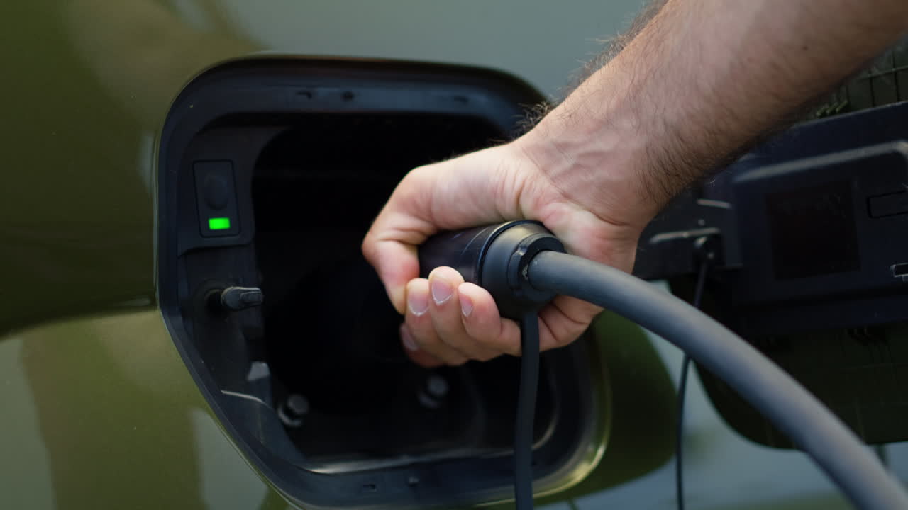 Extreme Closeup Of Eco Conscious Driver Connecting Electric Car To Charging Port