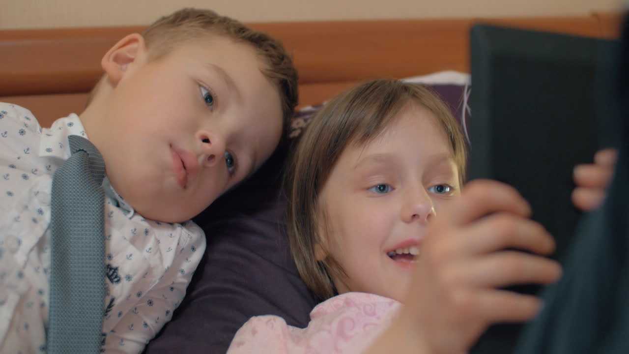 소년과 소녀는 터치 패드 게임에 매료되었습니다.