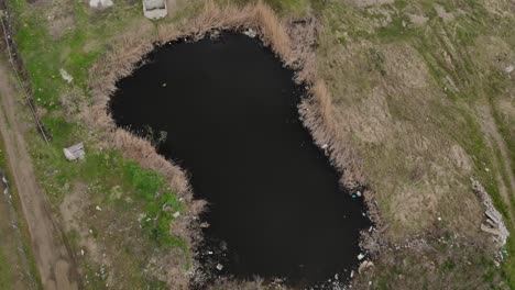 aerial view of a property with a small polluted lake darkened by waste