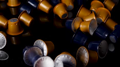 Close-up of Scattered Gold and Dark Blue Coffee Capsules on a Black Surface