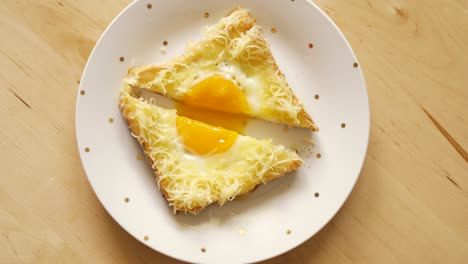 top view of toast with fried egg and cheese on wooden kitchen table