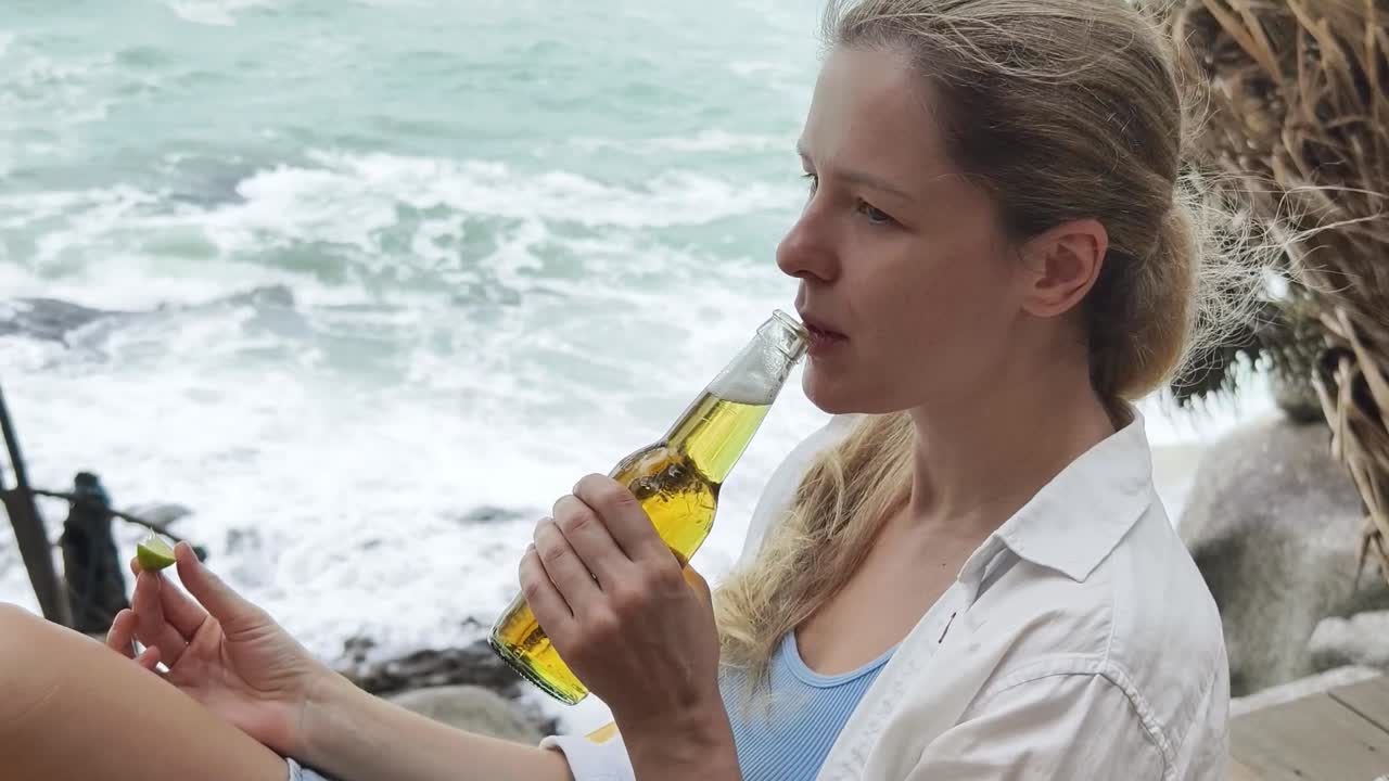 mujer bebiendo cerveza en la playa
