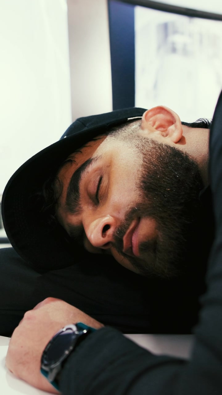 Young Man Sleeping on Desk in Modern Office