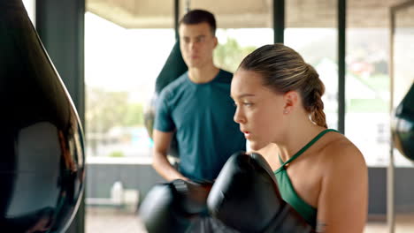 entrenador, mujer y saco de boxeo durante el entrenamiento