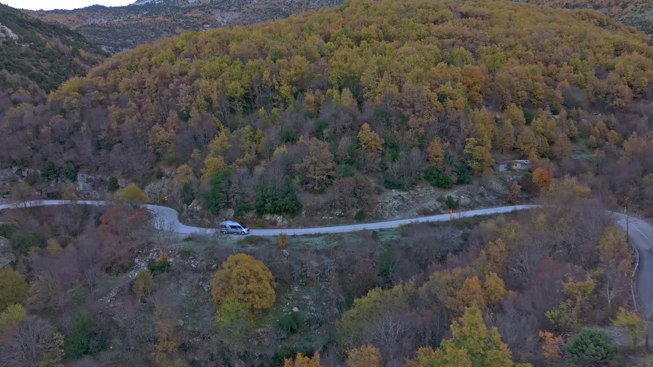 Dronebillede af varevogn, der kører gennem bjergskov, Papigo