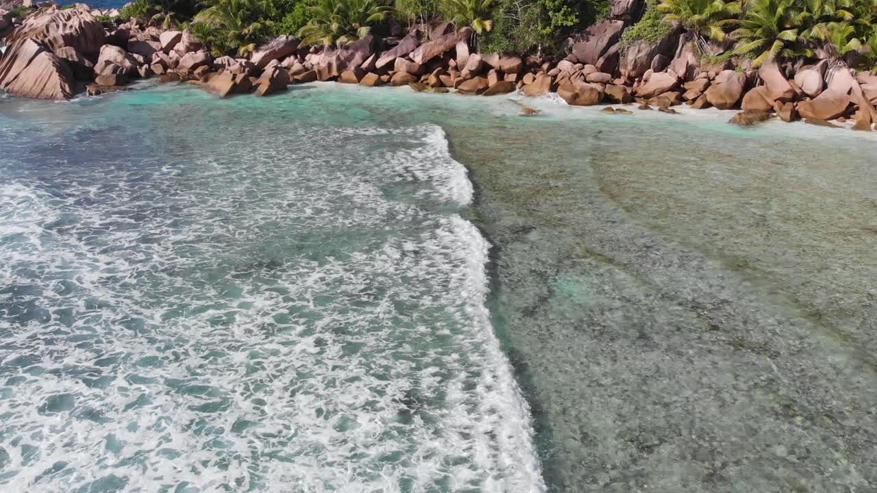 Pemandangan udara yang mengikuti ombak yang bergulir menuju pantai-pantai berpasir putih tak berpenghuni di Anse Coco, Petit Anse, dan Grand Anse di La Digue, sebuah pulau di Seychelles